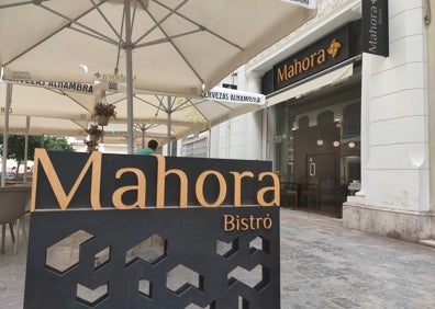 Imagen secundaria 1 - Arriba, terraza del restaurante Mahora Bistró. Abajo a la izquierda, fachada del local y valla con el logo. Abajo a la derecha, macetas del restaurante cuelgan de las sombrillas. 