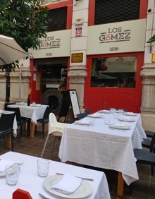 Imagen secundaria 2 - Arriba, terraza de Los Gómez Taberna con el Ayuntamiento de fondo. Abajo a la izquierda, detalle del jarrón decorativo de una de las mesas. Abajo a la derecha, fachada del restaurante. 