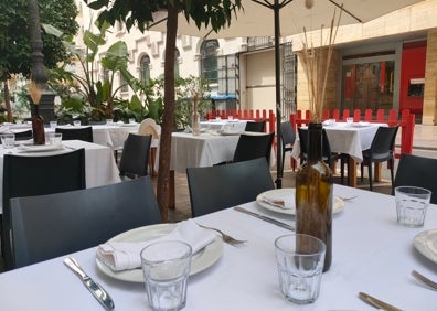 Imagen secundaria 1 - Arriba, terraza de Los Gómez Taberna con el Ayuntamiento de fondo. Abajo a la izquierda, detalle del jarrón decorativo de una de las mesas. Abajo a la derecha, fachada del restaurante. 