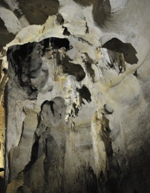 Imagen secundaria 2 - Arriba, un visitante observa los altos techos de la sala de la Ermita. Abajo a la izquierda, la plataforma de madera, que se encuentra iluminada por pequeños faroles. Abajo a la derecha, formaciones en las paredes de la gruta. 