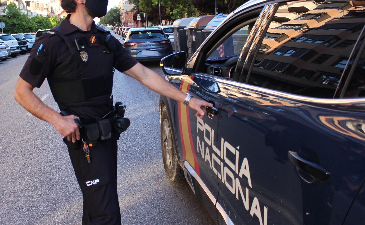 Un policía nacional junto a un coche patrulla. 