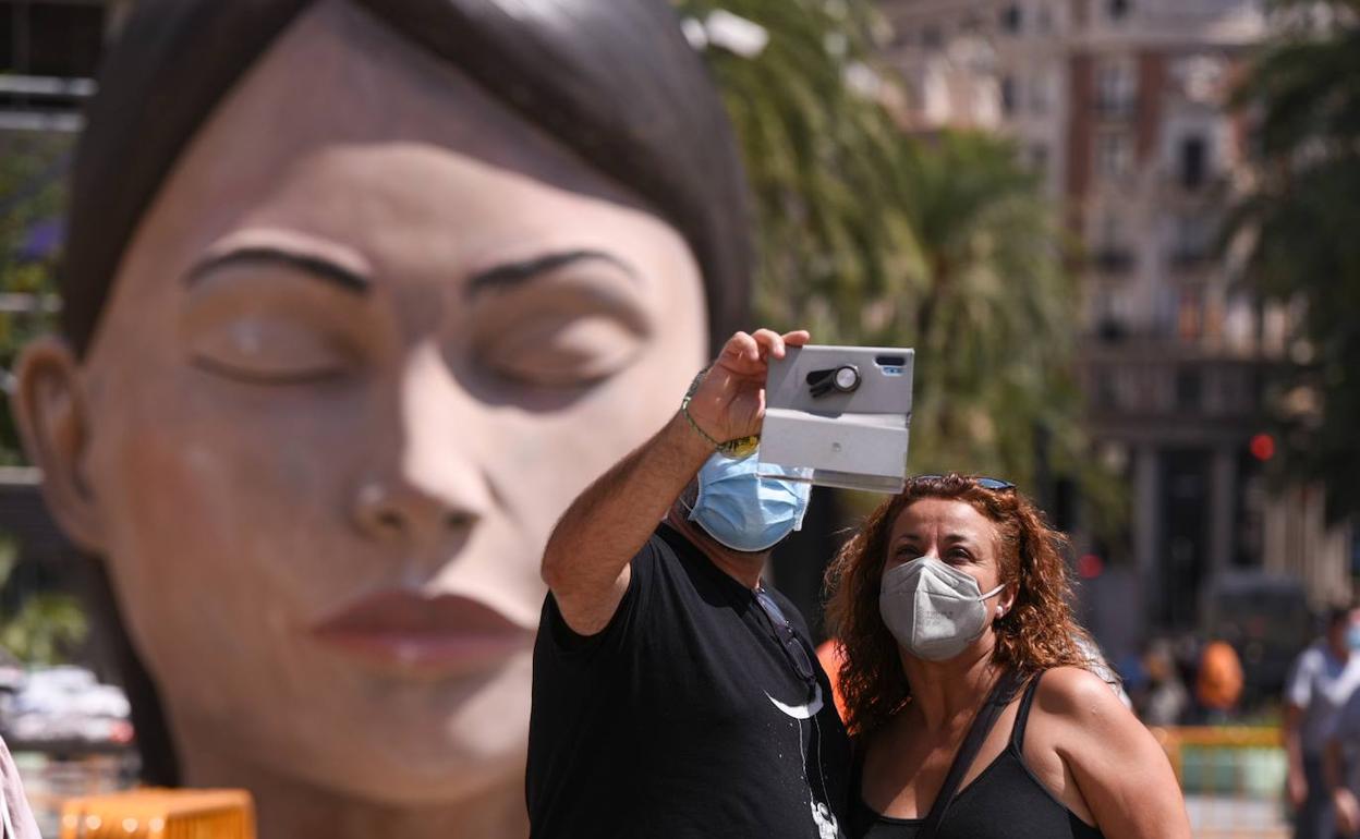 Una pareja se fotografía con la 'Meditadora' detrás en la plaza del Ayuntamiento. 