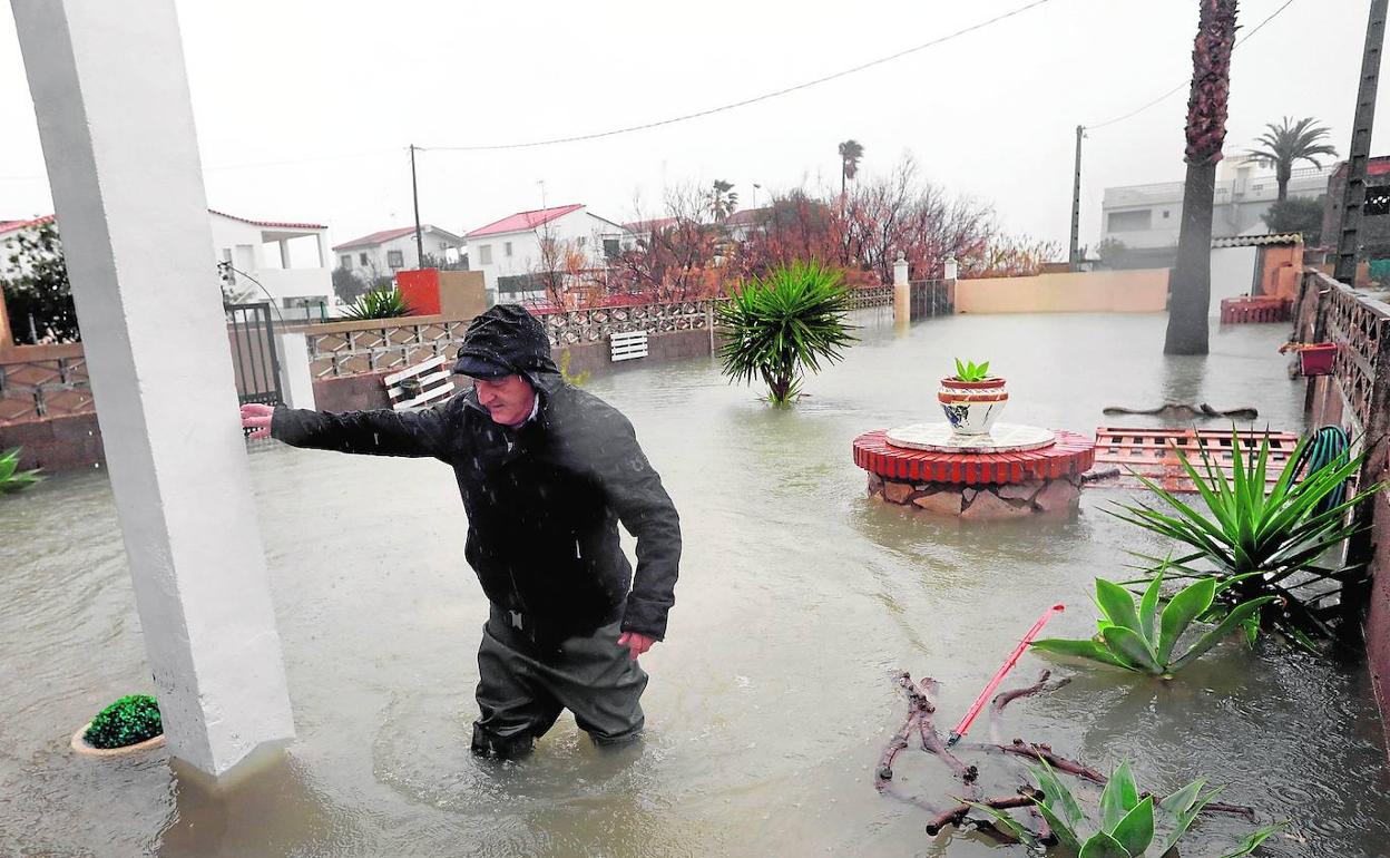 Un hombre intenta acceder a su casa afectada por el temporal 'Gloria'. 