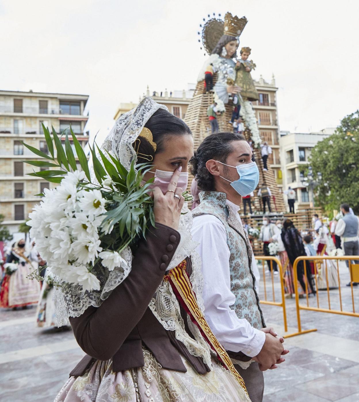 Una pareja fallera desfila con mascarilla ante la imagen de la 'Geperudeta' en la Ofrenda. iván arlandis