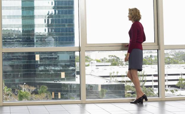 Una mujer mira por la ventana de una oficina. 