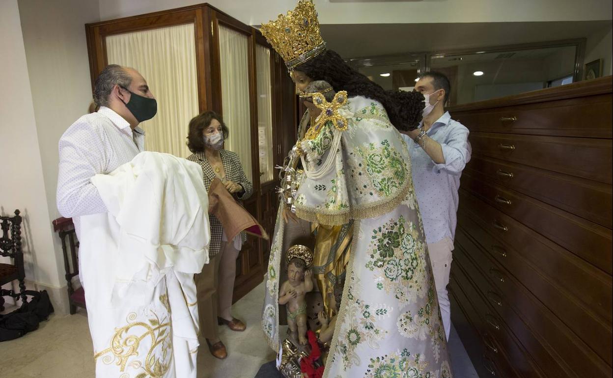 Francisco Perales (izquierda) lleva en sus brazos el nuevo manto para la Virgen, cuya imagen está vestida con una pieza de traslado.