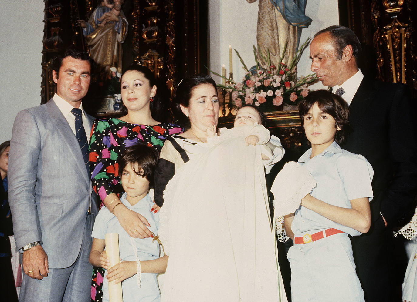 Doña Ana (centro) sostiene a Kiko Rivera en su bautizo, junto a una joven Isabel Pantoja (izquierda).