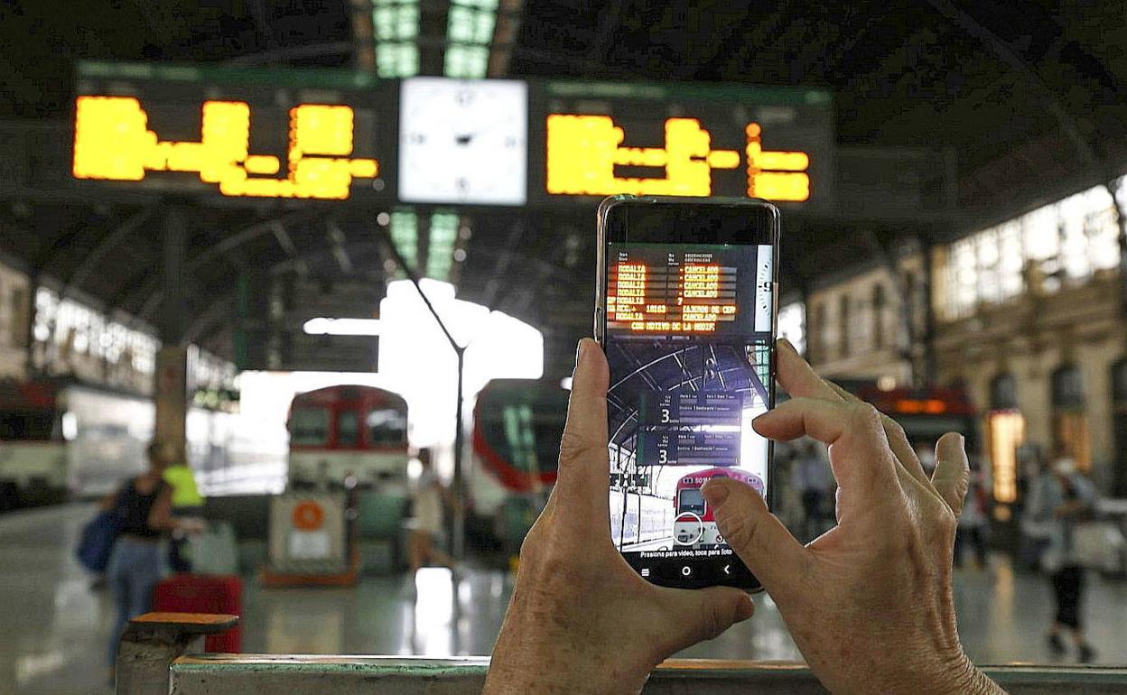 Una persona fotografía el panel informativo de la Estación del Norte que muestra las canelaciones de trenes por falta de maquinistas. 