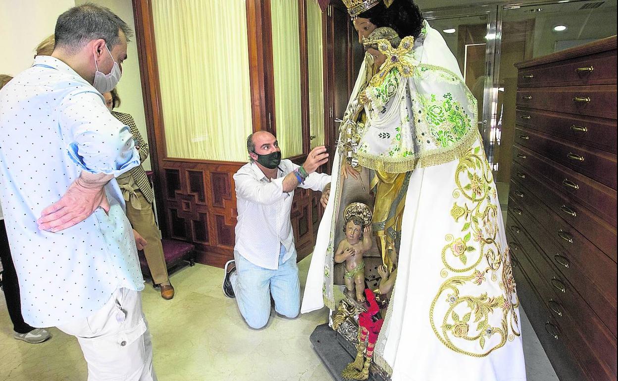 Francisco Perales (arrodillado) coge con alfileres el manto en la prueba que se realizó sobre la Peregrina. 