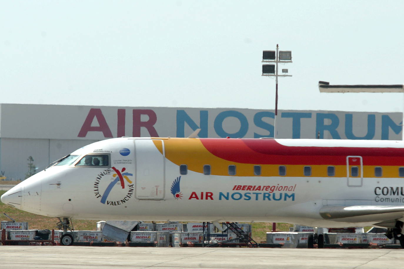 Un avión pasa ante instalaciones aeroportuarias de Air Nostrum. 