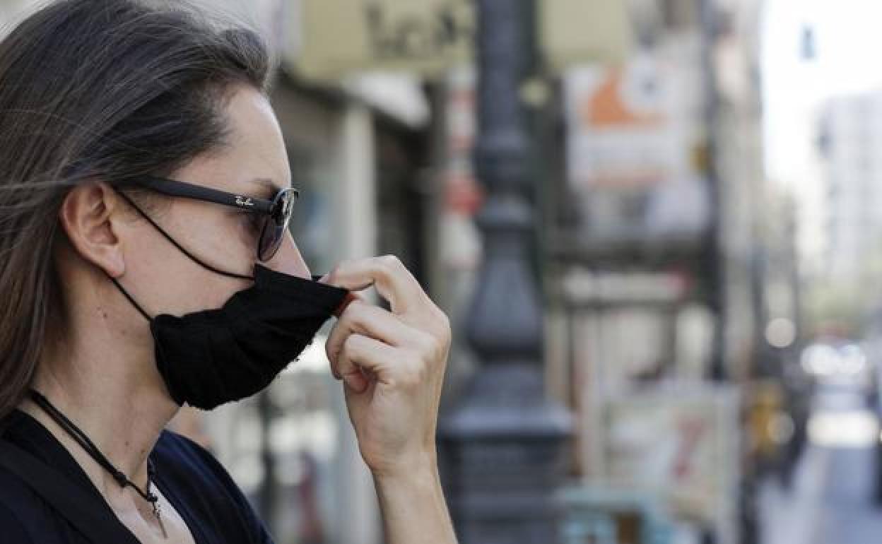 Una mujer se coloca la mascarilla