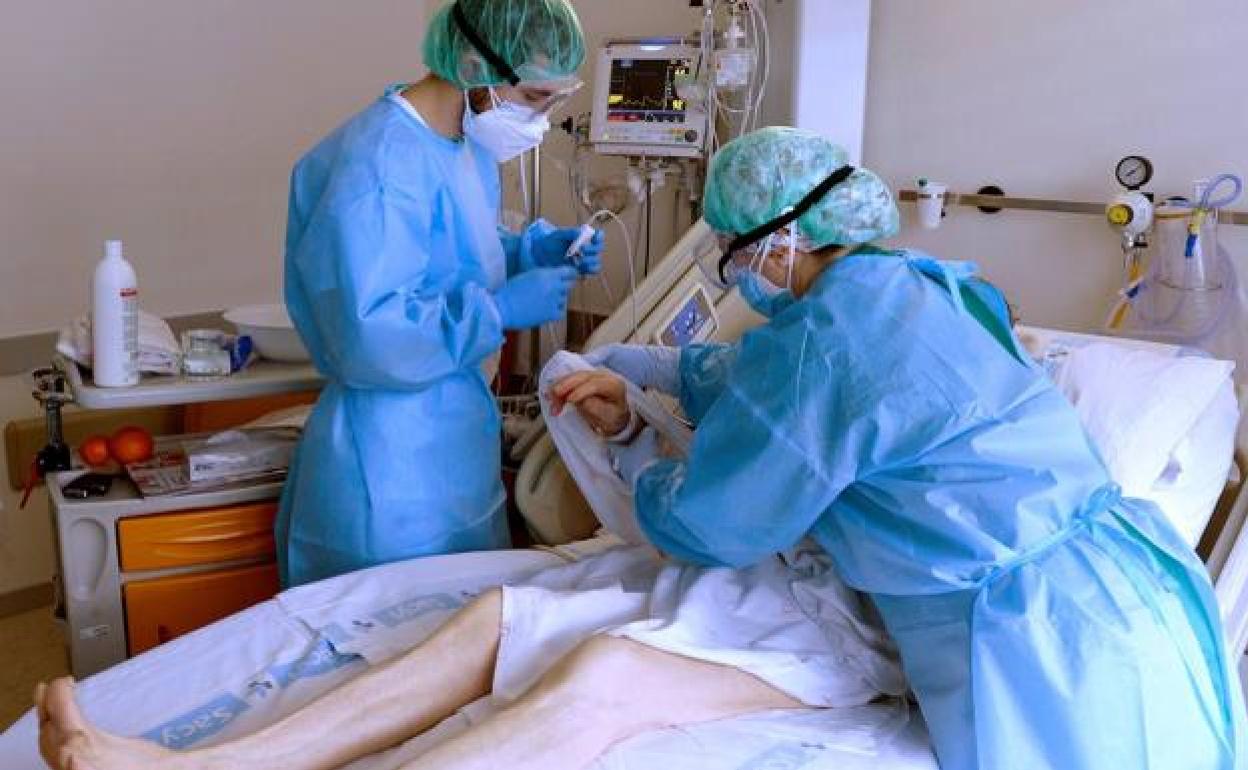 Dos sanitarios atienden a un paciente con covid en un hospital. 