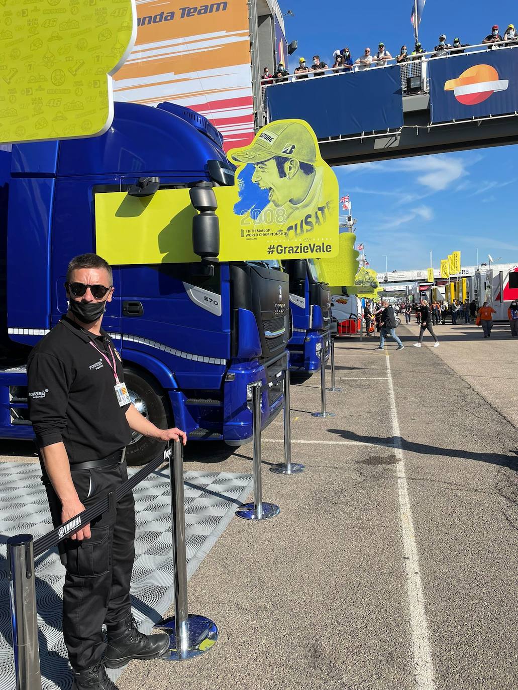 El paddock se ha teñido de amarillo este fin de semana. Como las gradas, que el sábado ya han expresado una muestra de intención de lo que será la carrera de este domingo. No es para nada exagerado afirmar que el 70% de los aficionados lucían merchandising de Valentino Rossi. Entre las muestras de homenaje que se le han dedicado por el momento, destaca la exposición de las nueve motos con las que ha sido campeón del mundo. Al lado está la 'Piazza Valentino Rossi', rotulada con una placa que simula ser de mármol y donde hay unos paneles amarilos que expresan los principales hitos del mito transalpino a lo largo de su carera. Más allá de esto, la mayoría de los camiones de los equipos tienen un panel, del mismo diseño, como muestra de gratitud al piloto por haber potenciado el Mundial de MotoGP durante sus más de 25 años de carrera. El propio piloto, en su mono, luce en la parte posterior este fin de semana un escueto pero representativo: 'Grazie'.