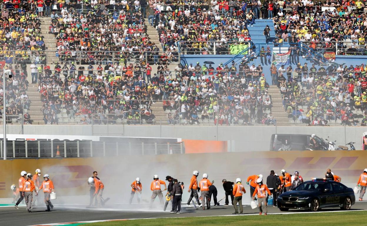 Aficionados en la grada mientras los operarios limpian la pista tras el accidente en la primera salida de Moto2. 