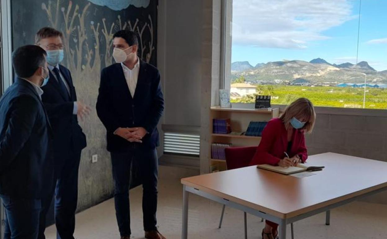 La ministra Pilar Alegría firma en el libro de honor, ante el president Puig, el conseller Marzà y el alcalde de La Font, con la sierra de la Safor y el Mondúver de fondo. 