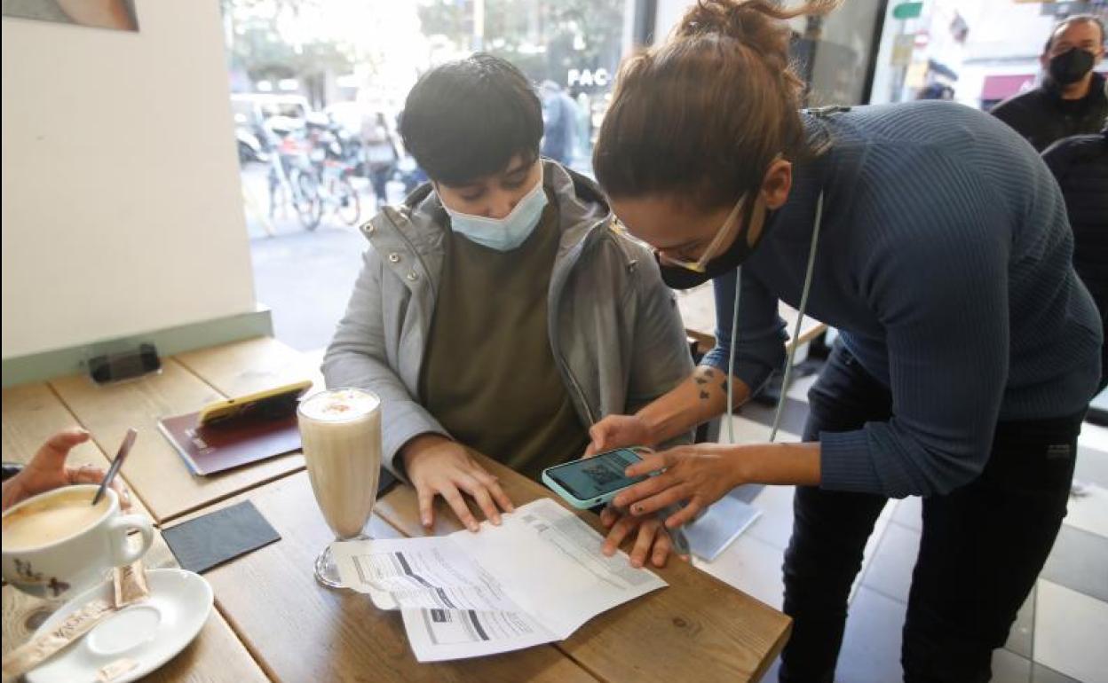 La trabajadora de una cafetería escanea el pasaporte Covid de los clientes.