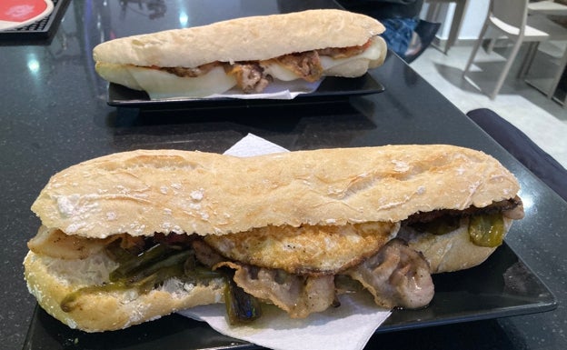 Imagen principal - Arriba, bocadillo de guanciale con pimientos fritos y huevo frito en primer plano, y con queso fundido y tomate refregado en segundo plano. Abajo a la izquierda, ensaladilla rusa casera del bar Bambú. Abajo a la derecha, plato de pisto aragonés. 