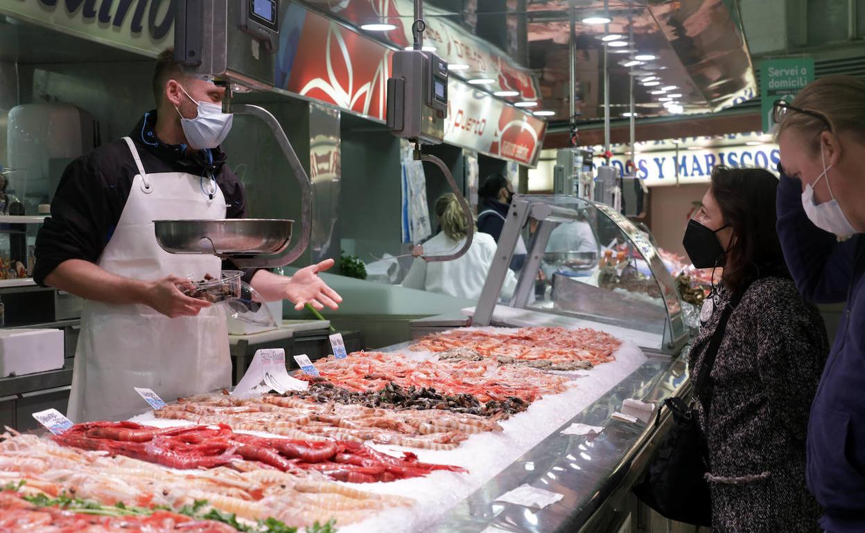 Un vendedor atiende a una mujer en una pescadería del Mercado Central de Valencia. 