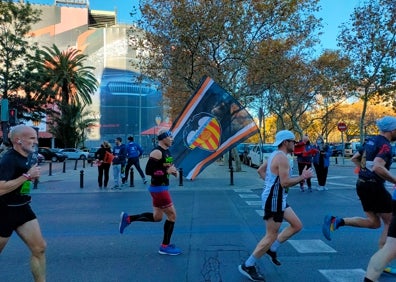 Imagen secundaria 1 - Arriba, la carrera frente al estadio de Mestalla. Abajo a la izquierda, los corredores pasan frente a una bandera del Valencia CF. Abajo a la derecha, el rat penat, símbolo del equipo, anima a los deportistas. 