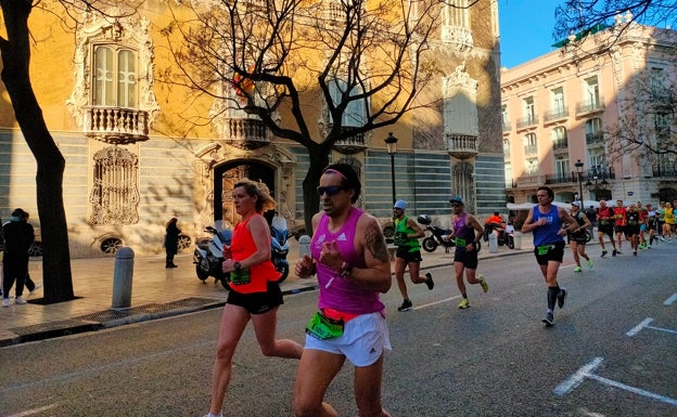 Imagen principal - Arriba, un grupo de corredores pasa frente al Palacio del Marqués de Dos Aguas. Abajo a la izquierda, los deportistas avanzan por la calle Poeta Querol. Abajo a la derecha, el Maratón a su paso por la iglesia de San Juan de la Cruz. 