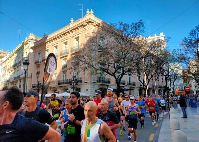 Imagen secundaria 1 - Arriba, un grupo de corredores pasa frente al Palacio del Marqués de Dos Aguas. Abajo a la izquierda, los deportistas avanzan por la calle Poeta Querol. Abajo a la derecha, el Maratón a su paso por la iglesia de San Juan de la Cruz. 