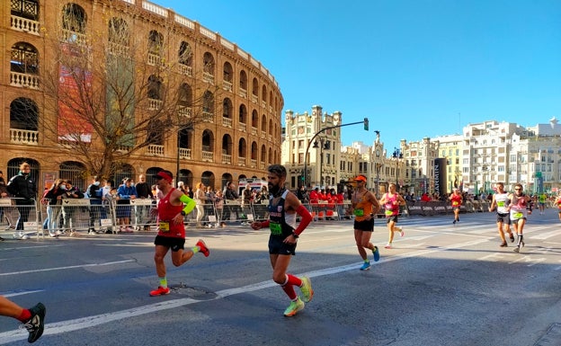 Imagen principal - Arriba, corredores a su paso frente a la plaza de Toros. Abajo a la izquierda, unos deportistas pasan frente a la plaza- Abajo a la derecha, la Maratón a su paso frente a la Estación del Norte. 