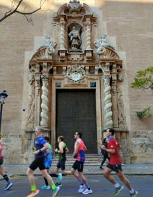 Imagen secundaria 2 - Arriba, un grupo de corredores pasa frente al Palacio del Marqués de Dos Aguas. Abajo a la izquierda, los deportistas avanzan por la calle Poeta Querol. Abajo a la derecha, el Maratón a su paso por la iglesia de San Juan de la Cruz. 