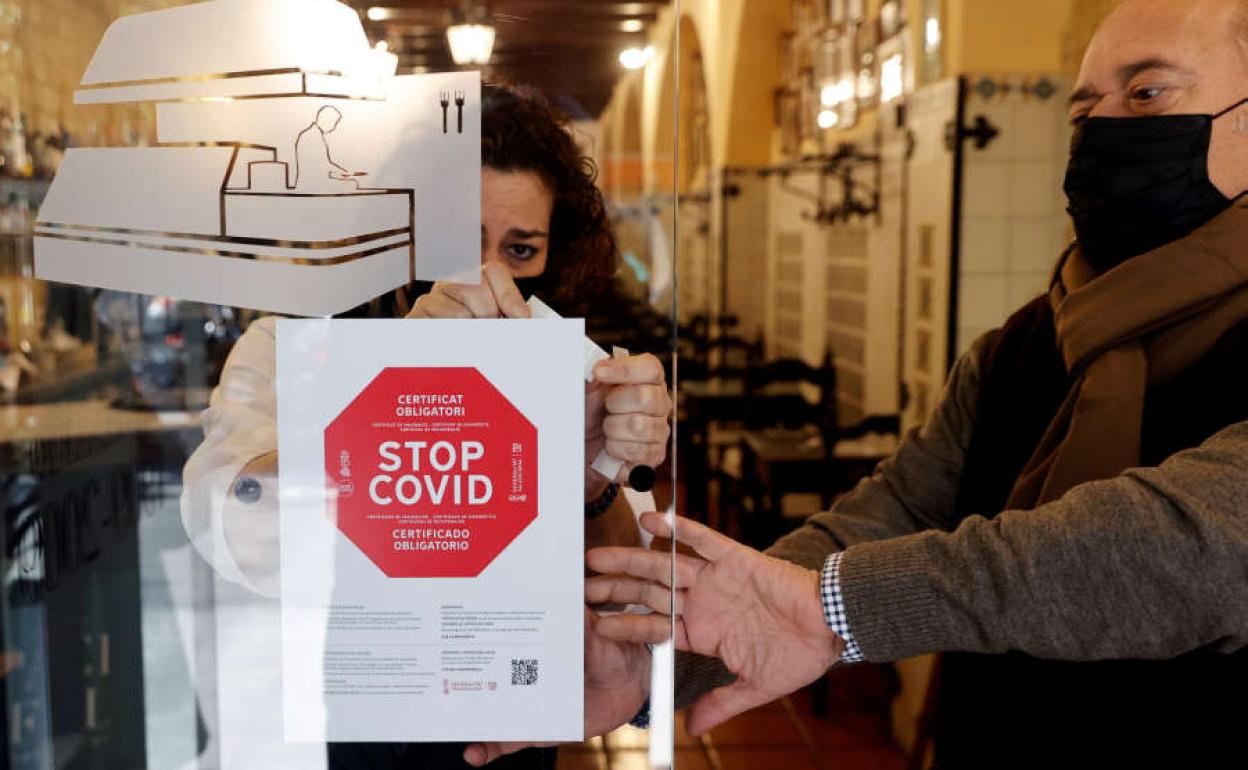 Un restaurante de la Comunitat coloca el cartel que señala la obligatoriedad de presentar el pasaporte Covid para acceder. 