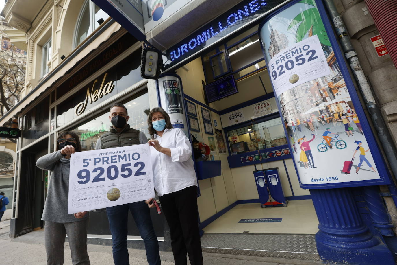 Los loteros de la administración número 13 de la ciudad de Valencia, en la plaza de Santa Catalina, que ha vendido una de las series del 92.052, lo que supone 60.000 euros en premios muestran el cartel anunciando el premio