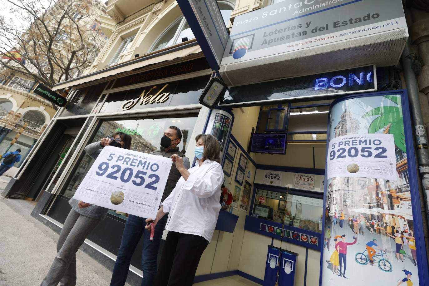 Los loteros de la administración número 13 de la ciudad de Valencia, en la plaza de Santa Catalina, que ha vendido una de las series del 92.052, lo que supone 60.000 euros en premios muestran el cartel anunciando el premio