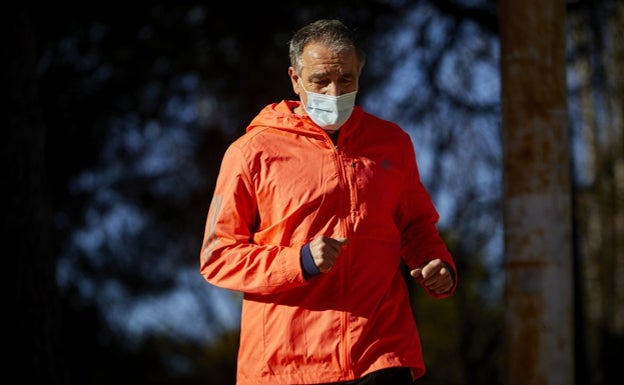 Un hombre corre por el lecho del río Turia con un cortavientos puesto.