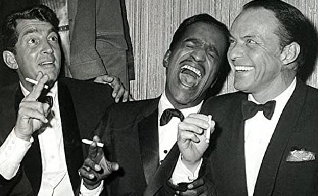 Imagen principal - Dean Martin junto a sus colegas del Rat Pack Sammy Davis Jr. y Frank Sinatra. En 'Río Bravo' con John Wayne y en una fotografía de 1980, con su eterno cigarrillo entre los dedos.