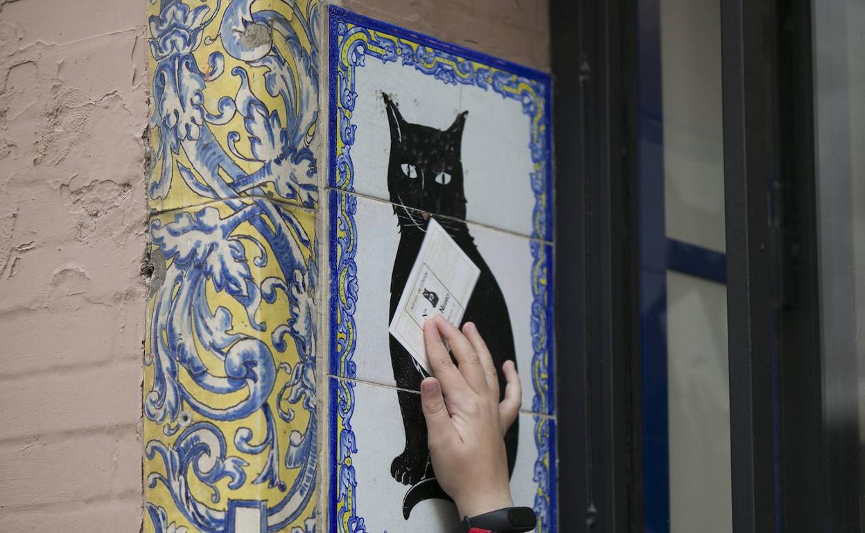 Un niño pasa un boleto de la lotería del Niño por el azulejo de la suerte de la administración de loterías El Gato Negro. 