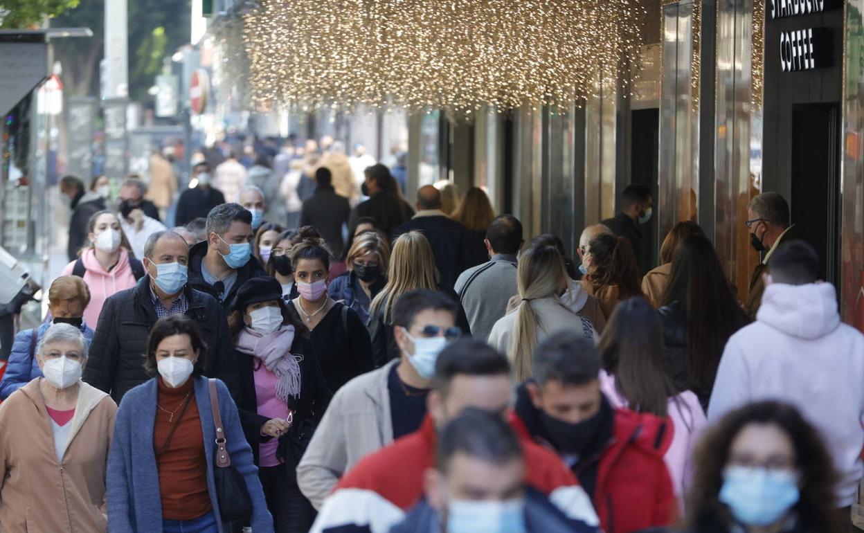 Decenas de personas recorren un tramo de la calle Colón junto a un centro comercial. 