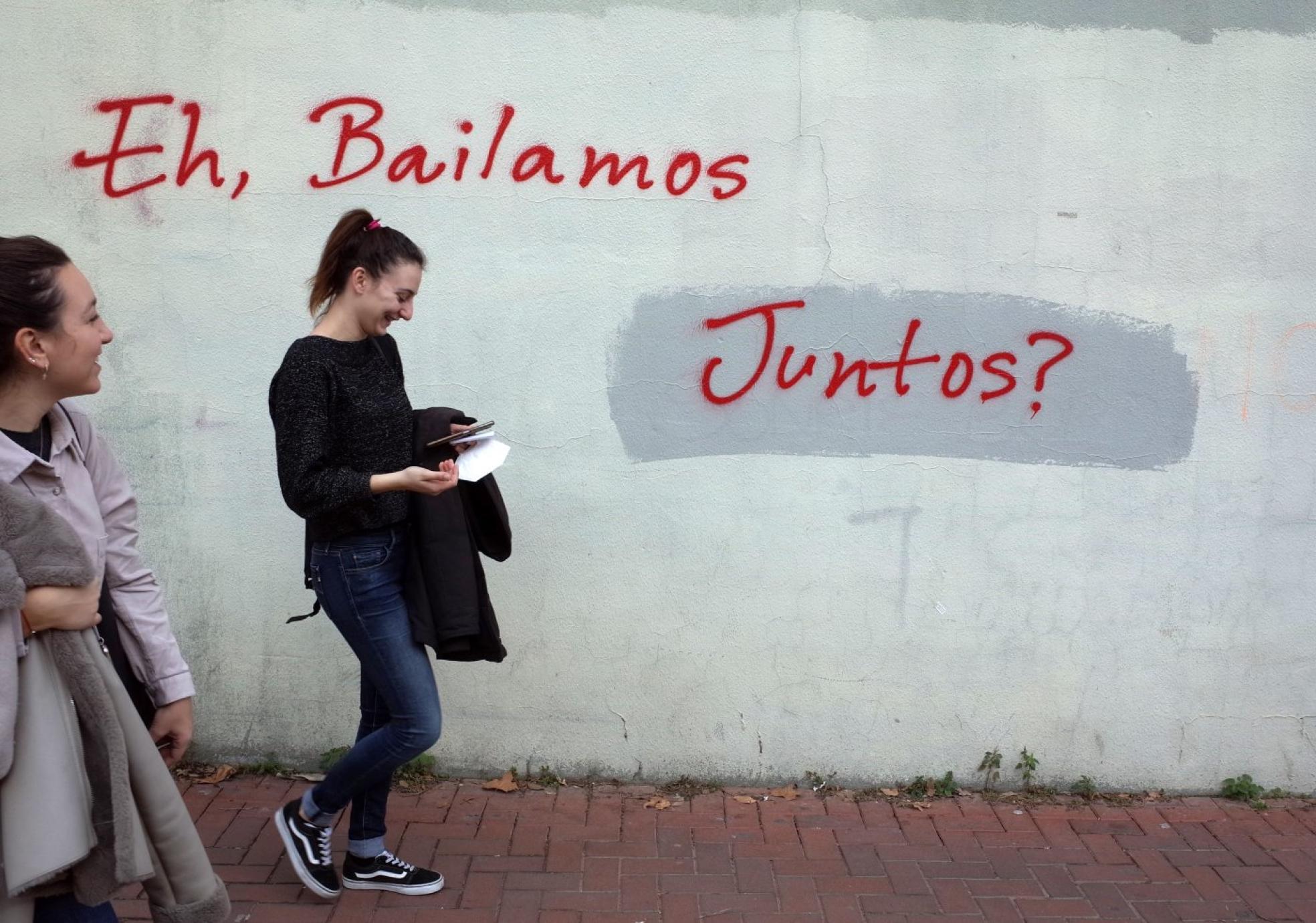 El vecindario. Una joven pasa junto a una pintada en el barrio. 