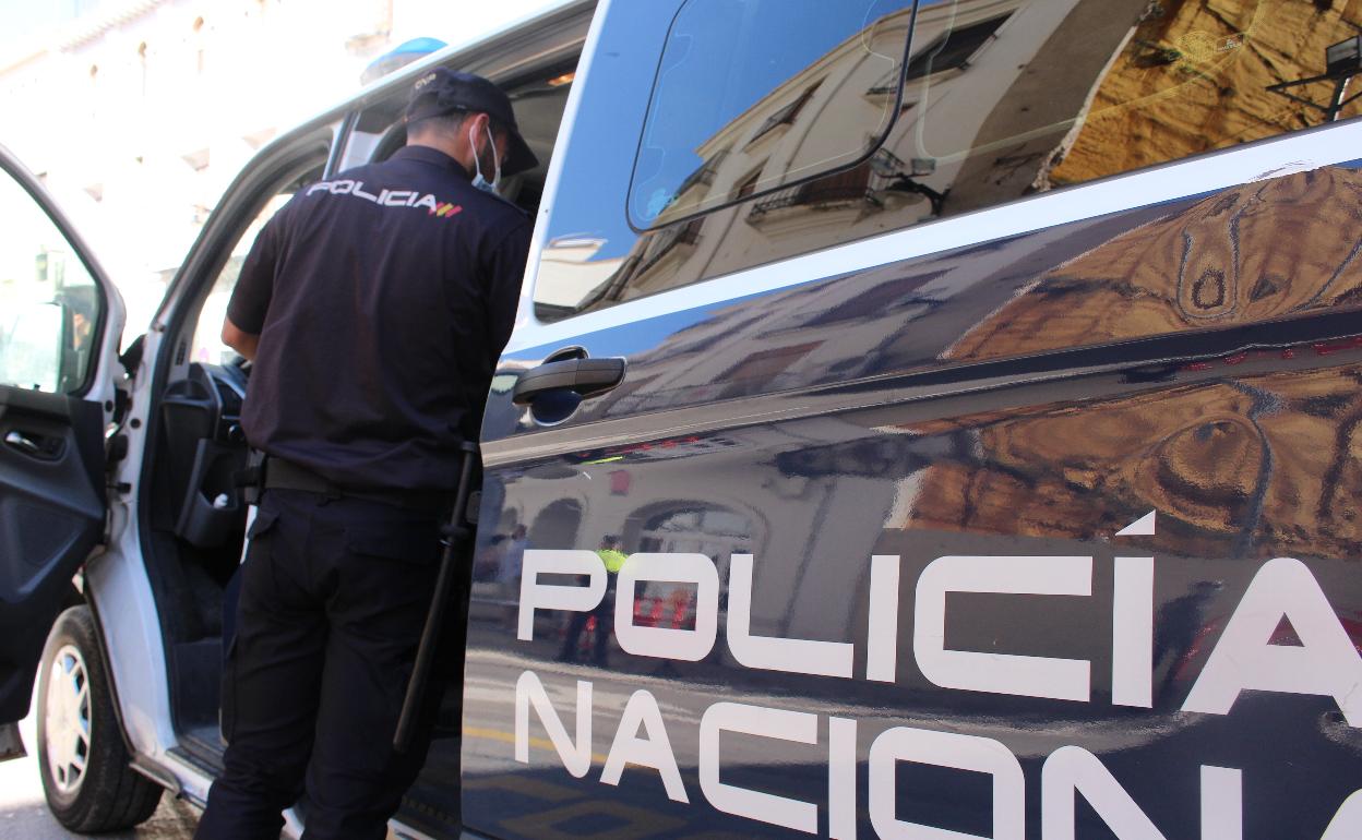 Un agente entra en un coche de Policía Nacional. 