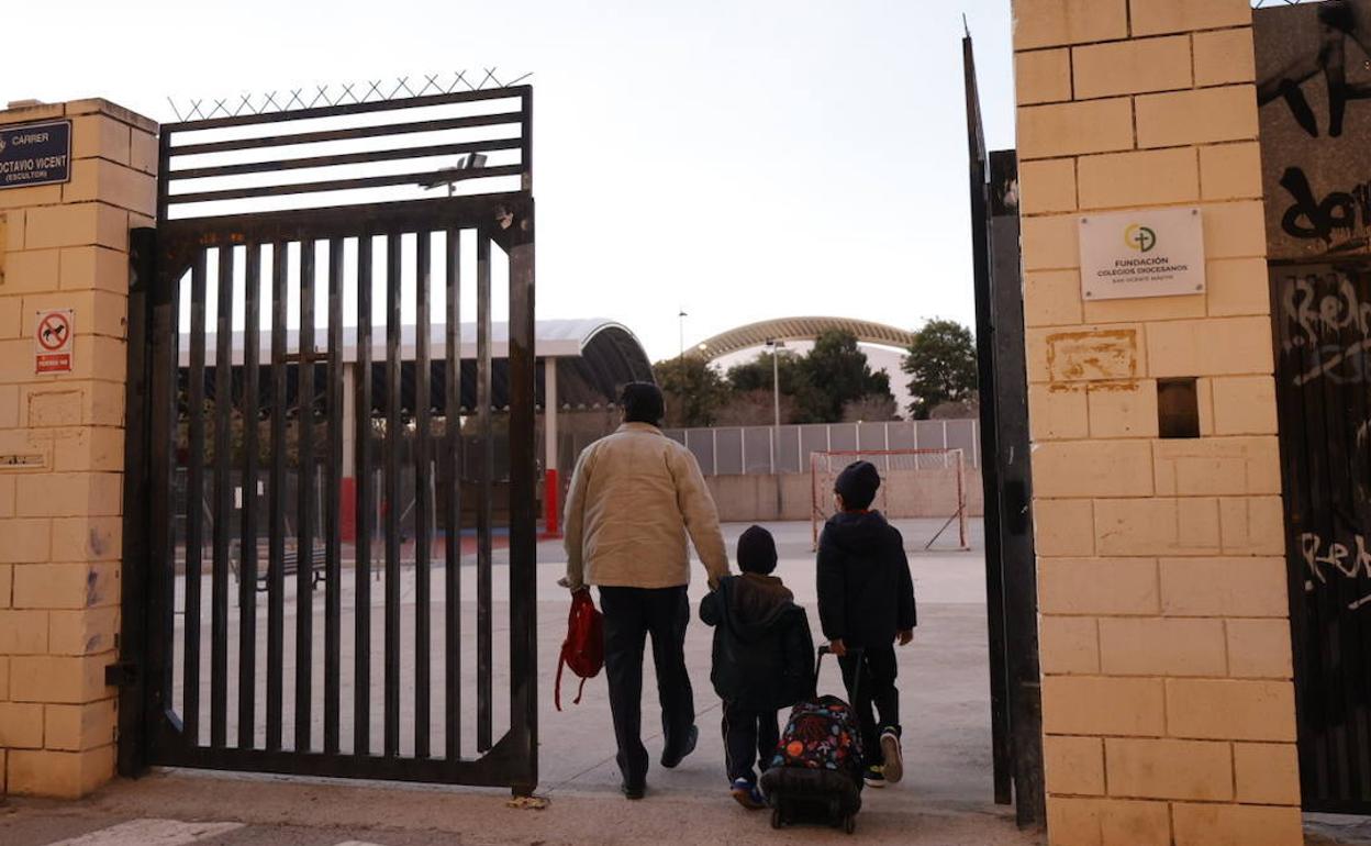 Un padre acompaña a sus hijos hasta la puerta del colegio. 