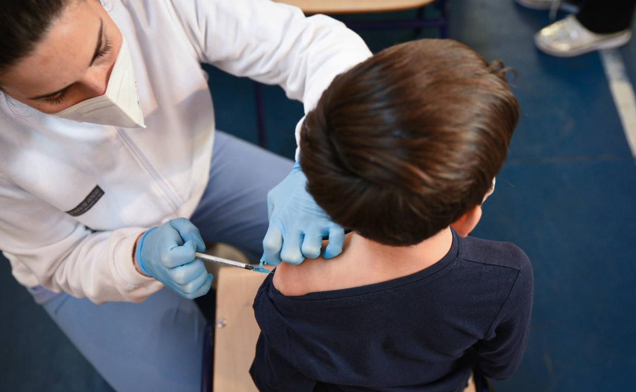 Una sanitaria vacuna a un menor en el colegio de infantil y primaria de Campanar. 