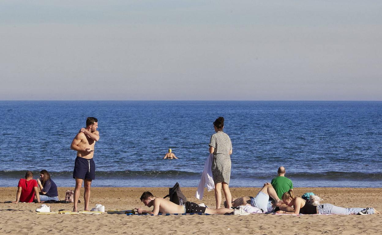 Personas disfrutando del sol en la playa de Valencia. 