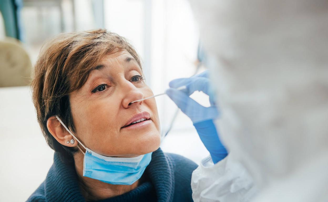 Una mujer con mascarilla se hace una PCR.