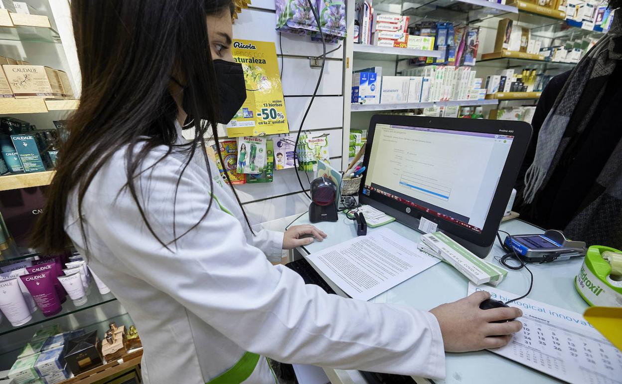 Una profesional registra los datos de un test en una farmacia valenciana.