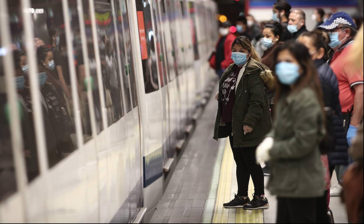 Gente con mascarilla esperando el metro.