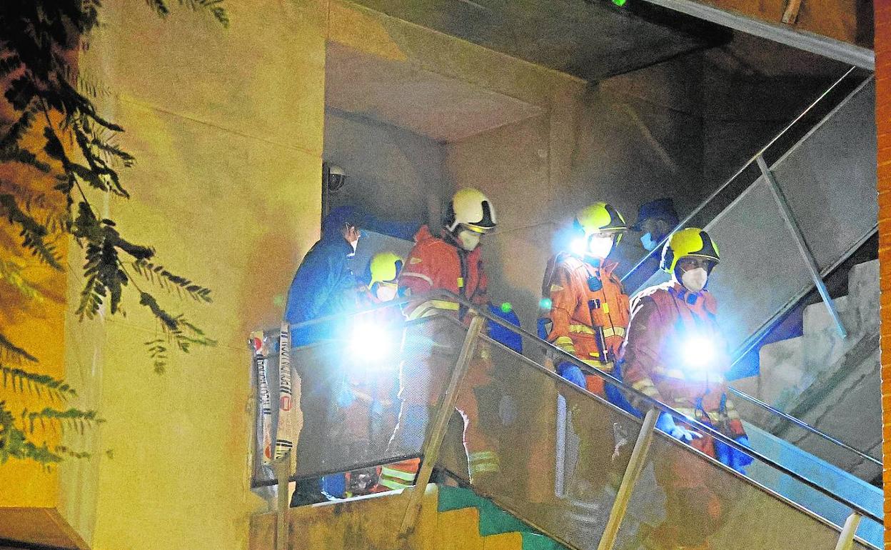 Los bomberos salen del primer piso de la residencia afectado por el incendio. 