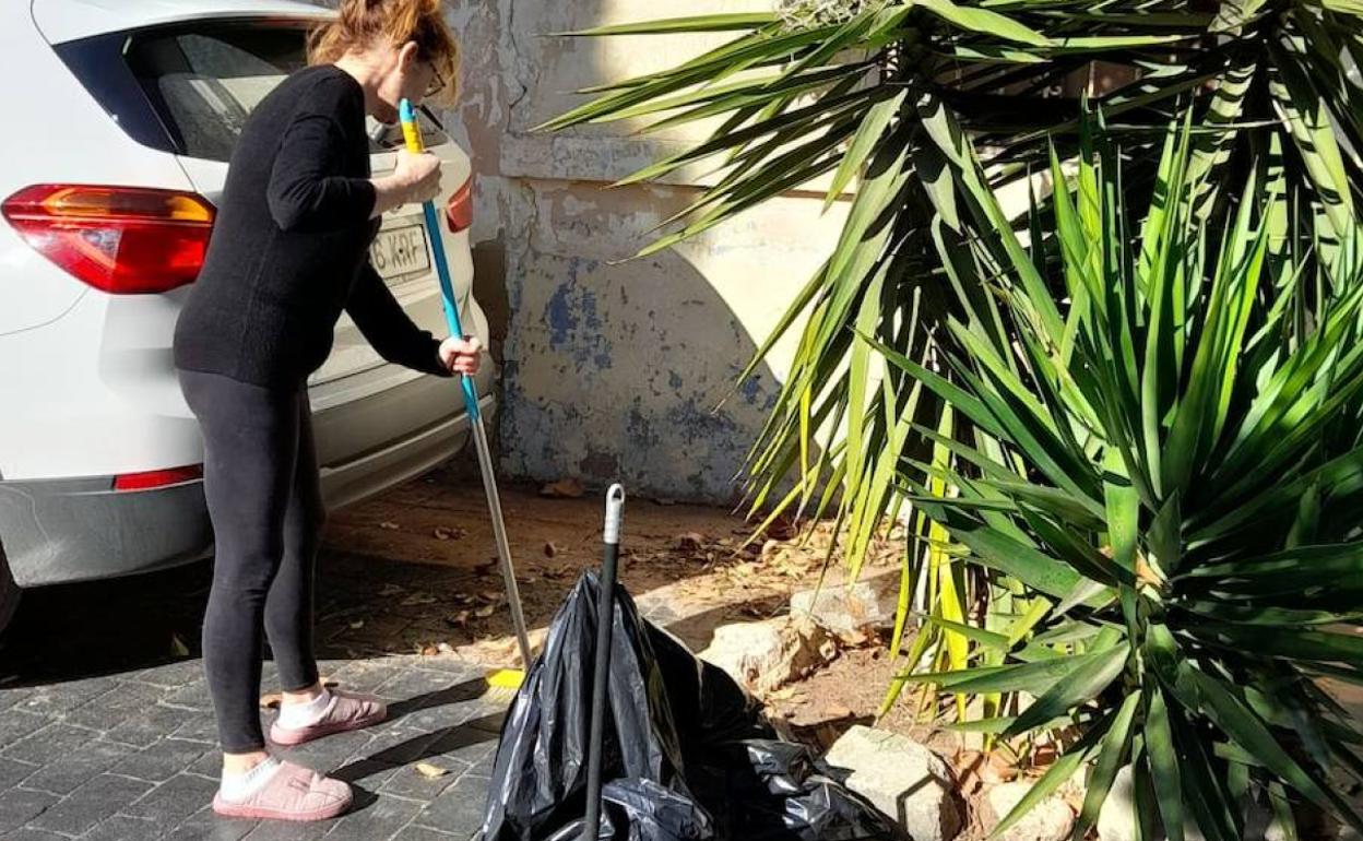 Una vecina barre una de las calles de la barriada. 