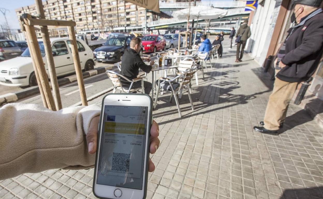 Un cliente muestra el pasaporte Covid antes de entrar en un bar. 