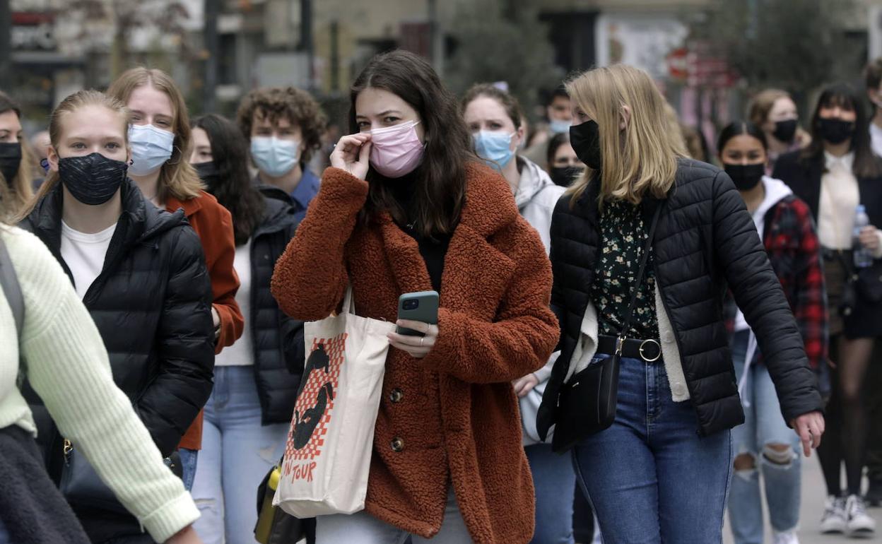 Viandantes con mascarilla por la calle. 