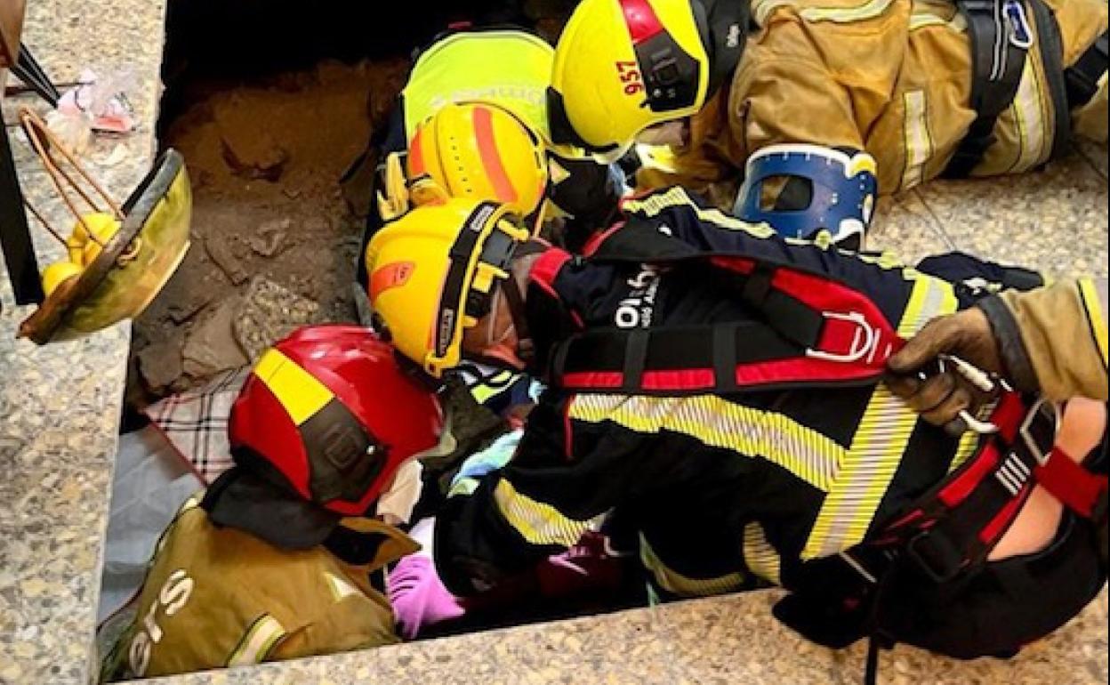 Los bomberos rescatan a la anciana tras ceder el suelo de su vivienda. 