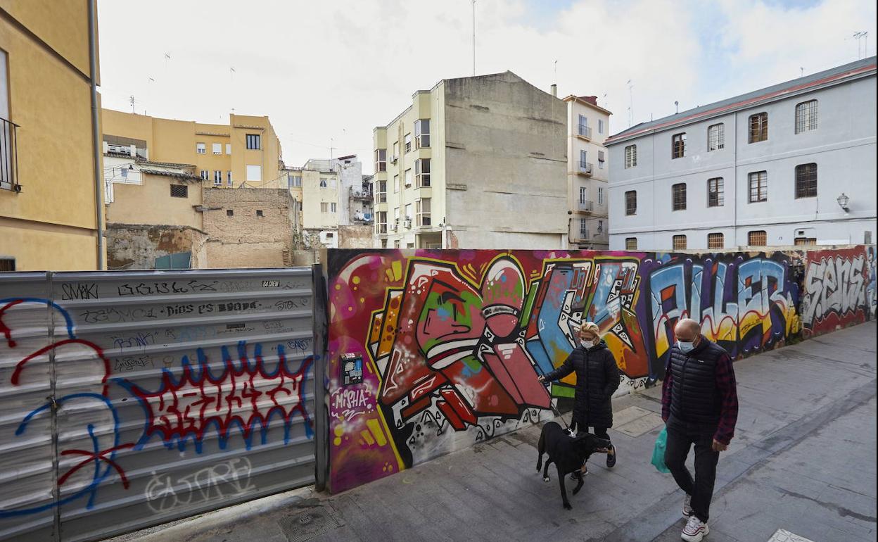 Dos vecinos pasan por uno de los solares del centro histórico de Valencia. 