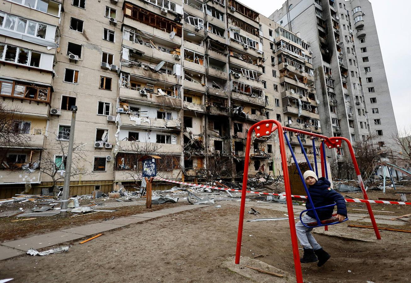 Un niño se columpia en los alrededores de un edificio destruido en Kiev.