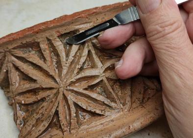 Imagen secundaria 1 - Rescate de la belleza de una pieza tan cotidiana como un plato. | Un técnico elimina restos de tierra de una pieza de cerámica. | Reconstrucción de una figura de mujer hallada en un solar de la calle Palomar. 